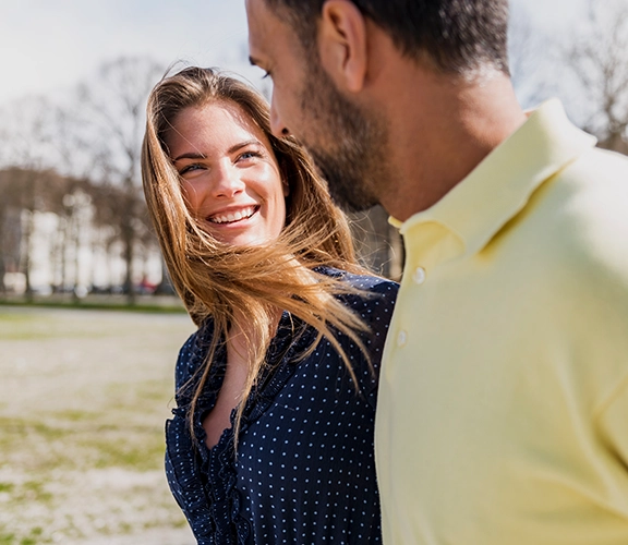 a man and woman walking and smiling at each other