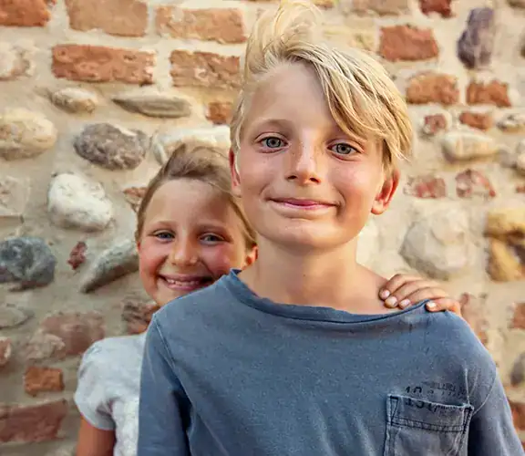 two young kids posing in front of a brick wall