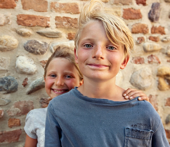 two young kids posing in front of a brick wall